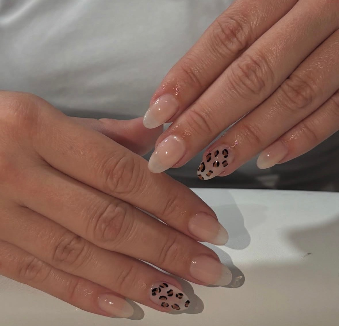 Glossy nude nails with leopard print accent